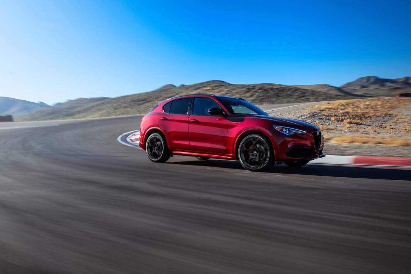 Alfa Romeo Stelvio 2022 Un VUS Alfa Romeo Stelvio 2022 rouge effectuant un grand virage sur une piste de course