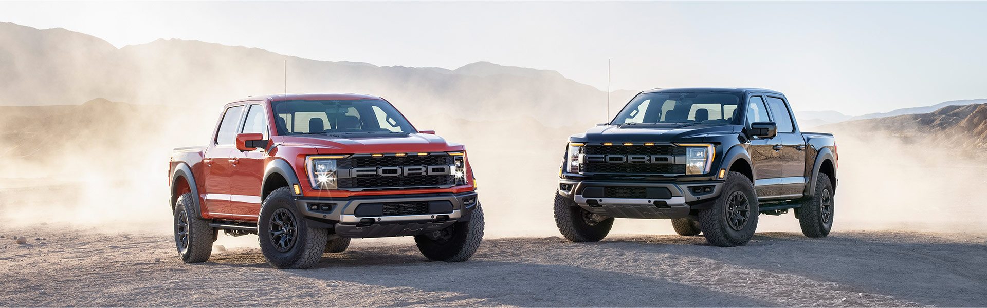 bn01_two_ford_2021_raptors_parked_side_by_side_in_desert_red_and_black.jpeg