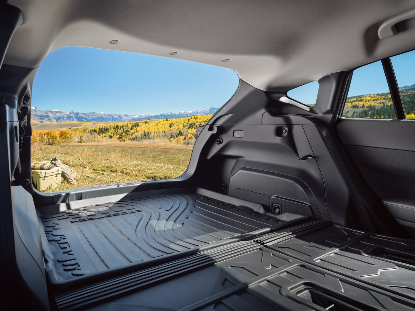 The Crosstrek's cargo area and cargo tray, looking out the open liftgate toward mountains