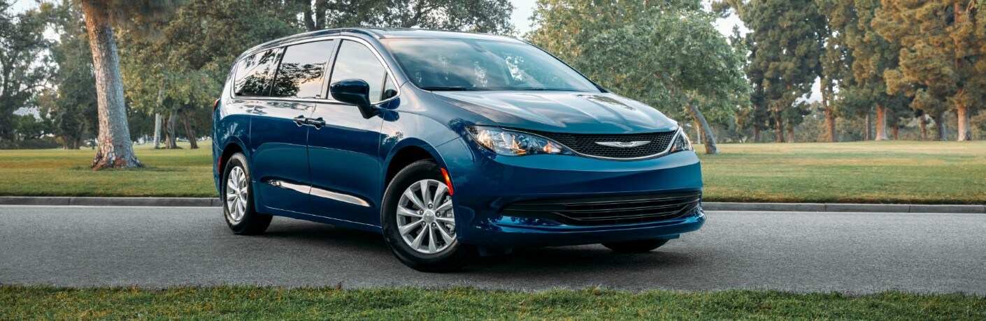 2020 Chrysler Voyager exterior shot with blue paint color parked on an asphalt road in a park near grass and trees