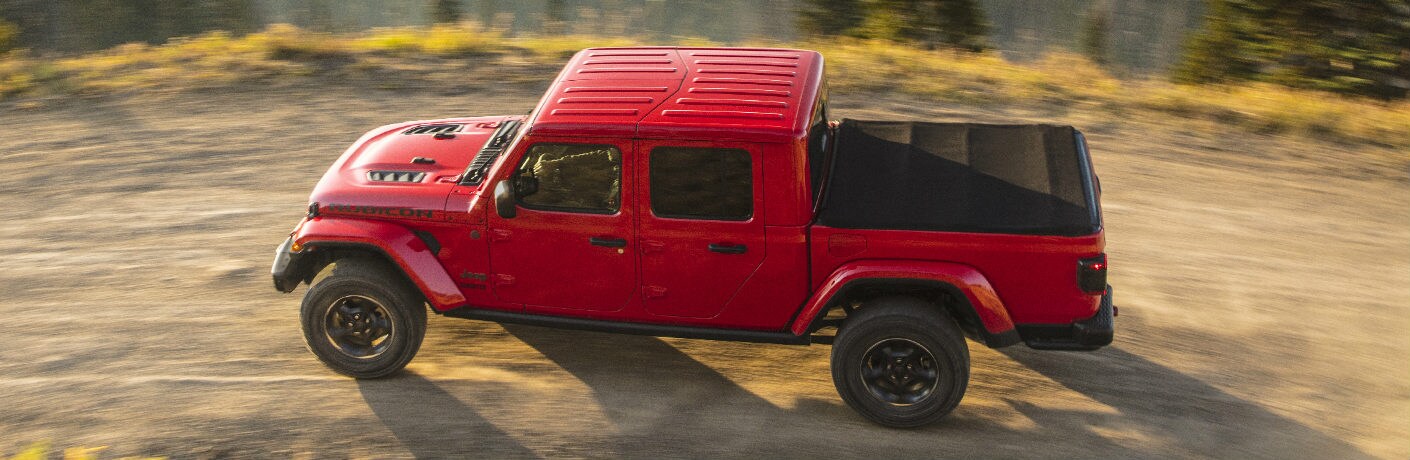 2020 Jeep Gladiator Rubicon interior overhead side shot with red paint color driving on a dirt country road in grass hills
