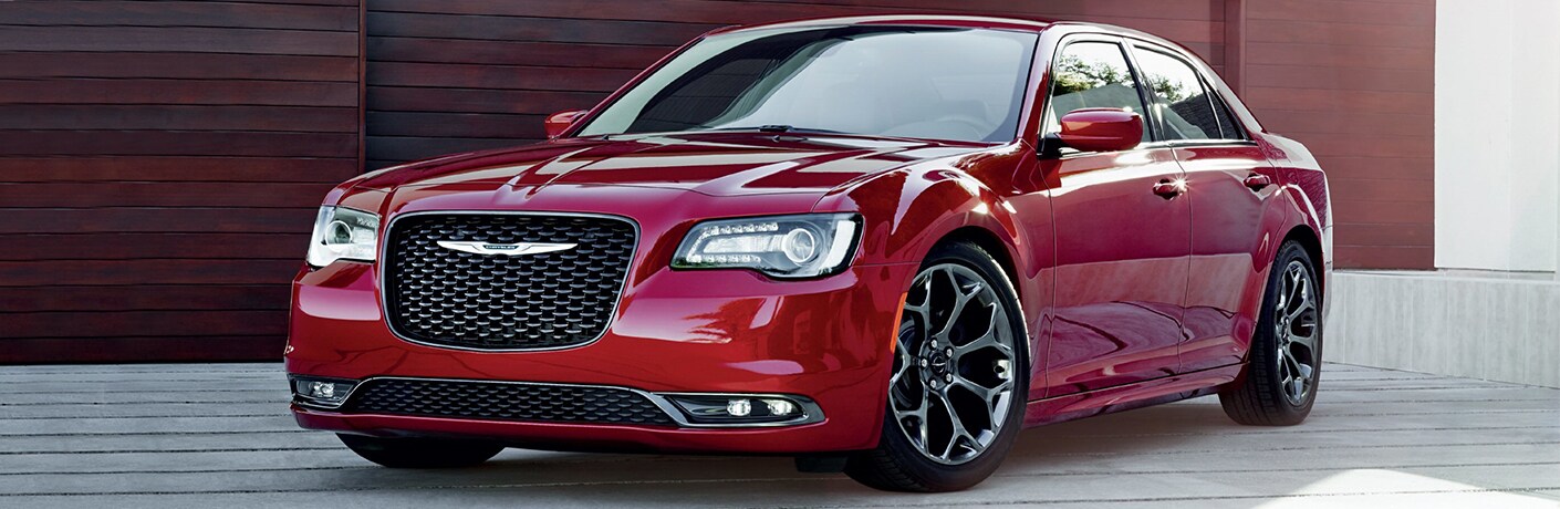 2019 Chrysler 300 exterior shot with red paint color parked on a wooden dock with red stained wood behind it