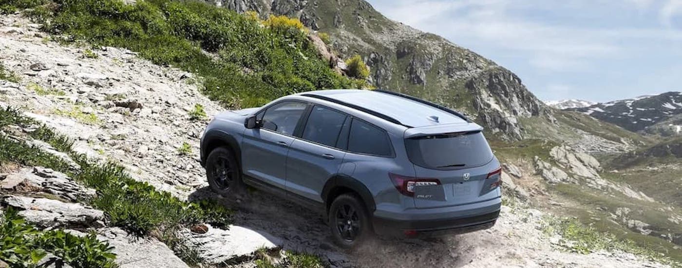 A grey 2022 Honda Pilot Trailsport is shown from the rear at an angle after leaving a dealer that has used suvs for sale.