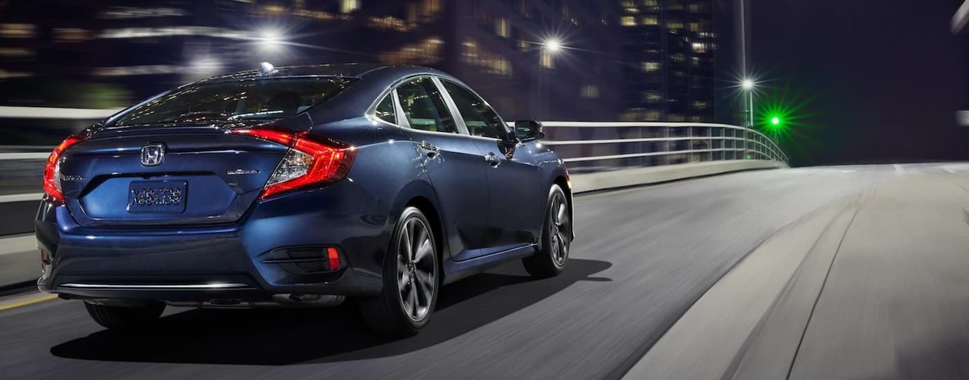 Used%20Honda%20Civic%20for%20Sale%20-%202020%20Honda%20Civic%20Sport%20-%20Night%20City.jpg Rear view of a blue 2020 Honda Civic Sport driving through a city at night.