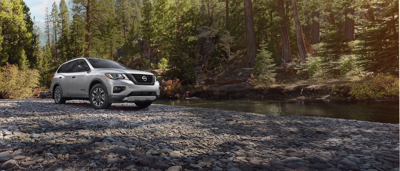 2020 Nissan Pathfinder A silver 2020 Nissan Pathfinder parked by a creek in the forest