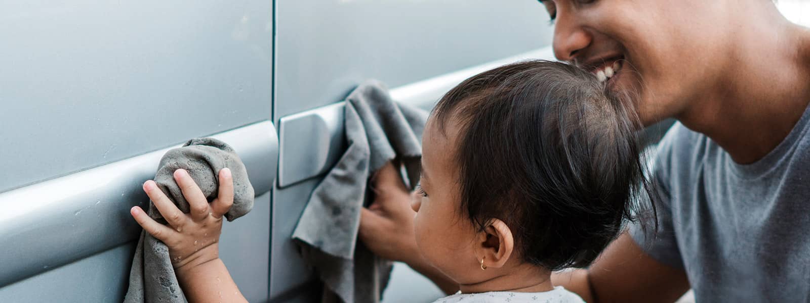 Parent teaching toddler how to wash a car properly