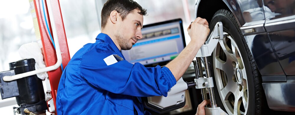 mechanic perfoms wheel alignment