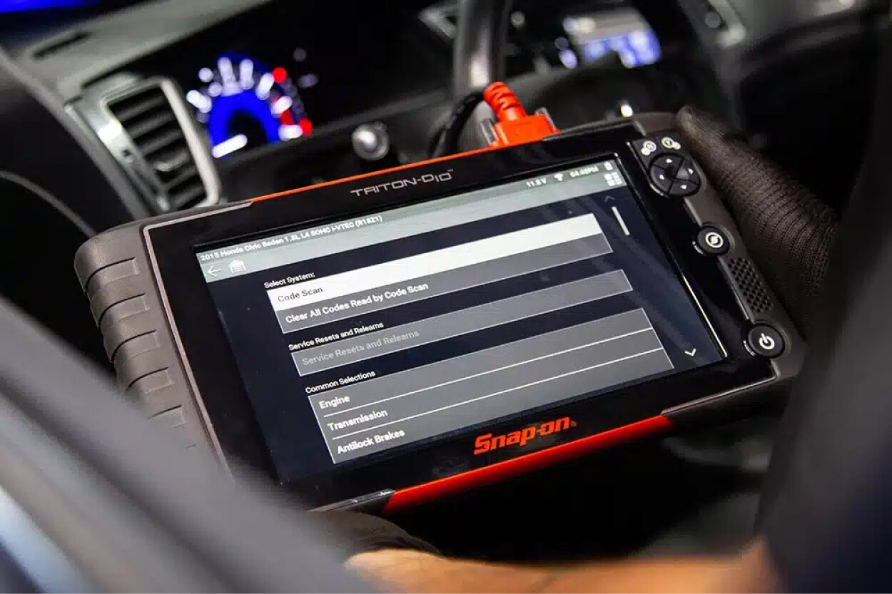 A Lincoln technician using a specialized digital battery tester on a luxury SUV.