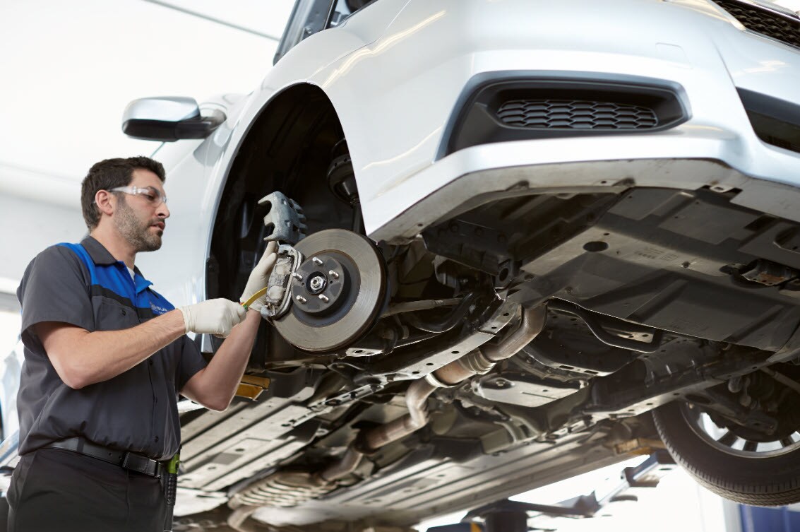 Subaru brake repair technician adjusting brake calipers and checking brake pads.jpg Subaru brake repair technician adjusting brake calipers and checking brake pads