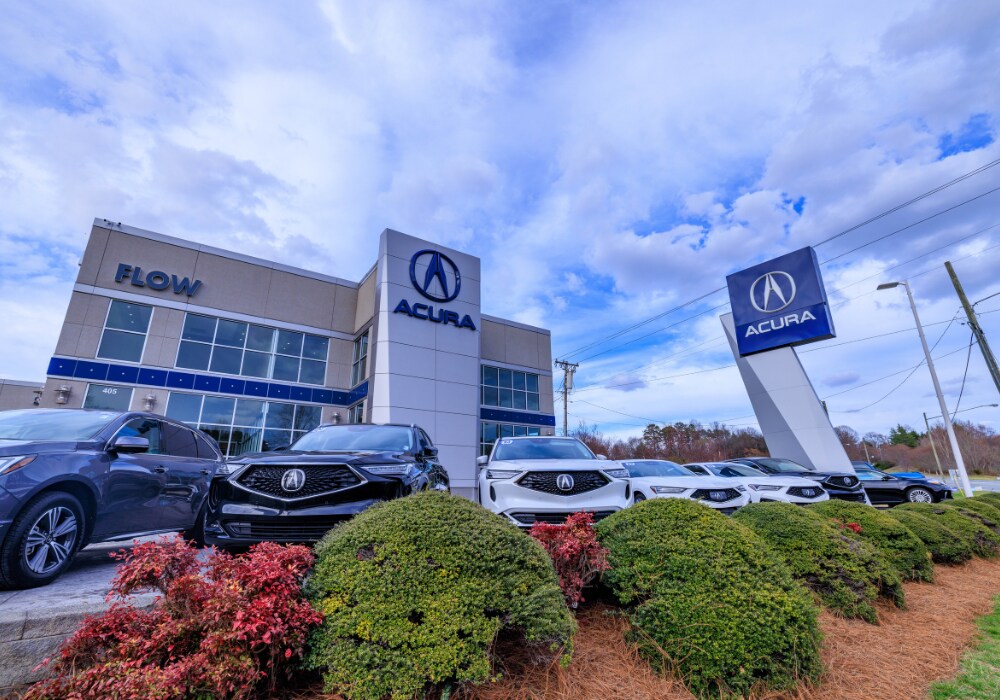 used-acura-for-sale.png A lineup of several Audi SUVs for sale in front of Flow Acura in Winston-Salem, NC. There is a blue cloudy sky in the background and green shrubs in the foreground