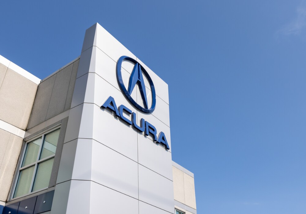 used-acura-cars-for-sale.png Acura name and logo on the exterior of the Flow Acura of Wilmington storefront. There is a blue sky in the background