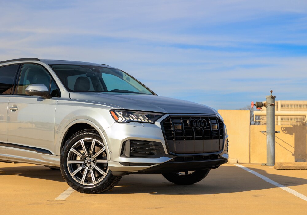 Gray 2024 Audi Q7 SUV parked with a lbue sky in the background. The back half of the vehicle is out of the frame