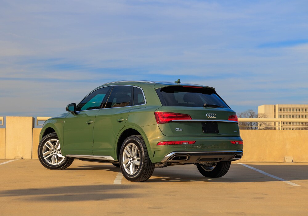Green 2024 Audi Q5 SUV parked on top of a parking garage. Photo shows the back left angle of the car