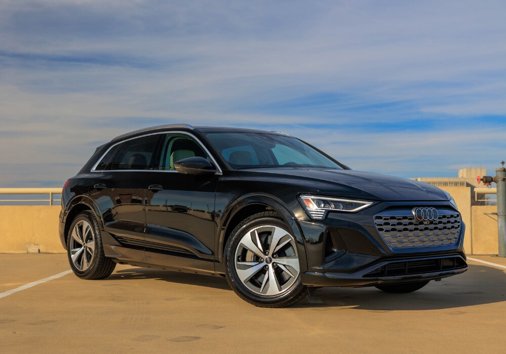 Photo of a black 2024 Audi Q8 e-tron for sale in Charlottesville, VA. The SUV is parked with a blue sky in the background