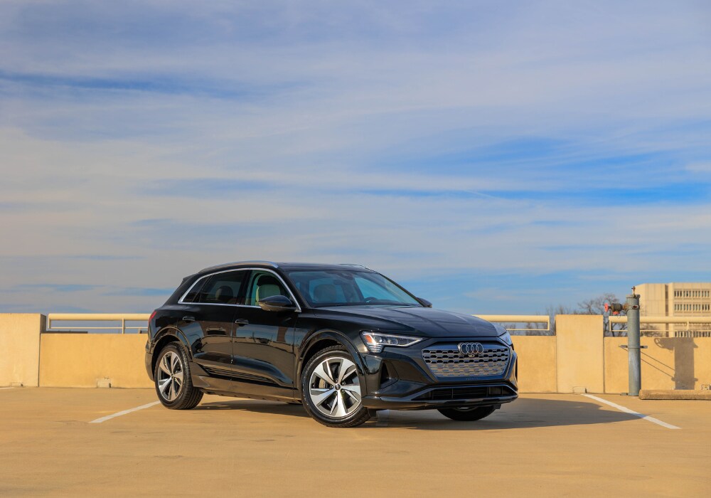 2024-audi-q8-e-tron.png Black 2024 Audi Q8 e-tron parked on the roof of a parking garage with the sky in the background