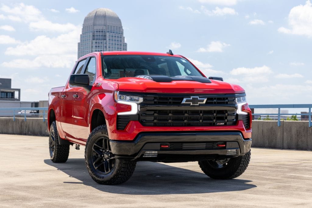 2024-chevrolet-silverado-1500.jpg Red Chevrolet Silverado 1500 truck parked with Winston-Salem skyline in the background