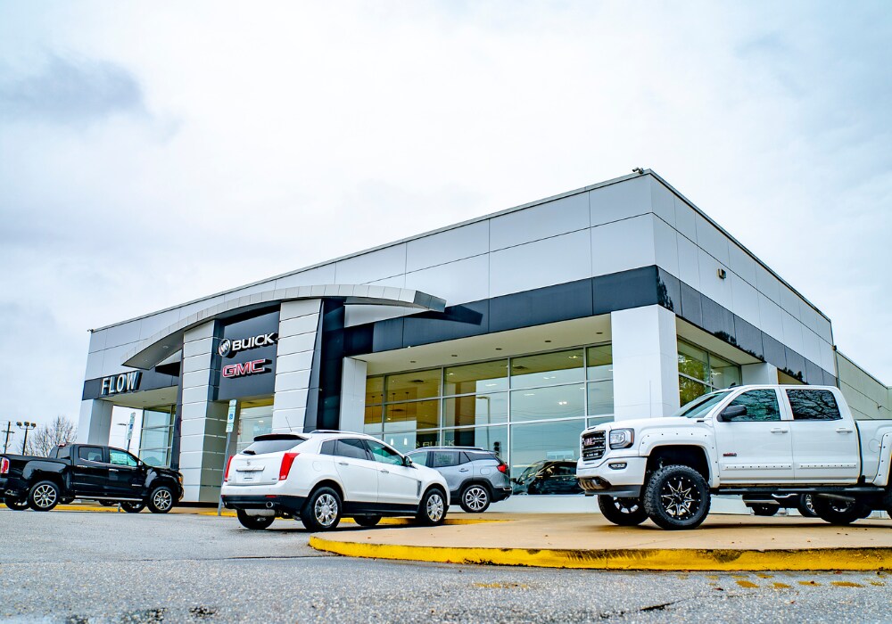 used-buick-gmc-for-sale-winston-salem.png Flow Buick GMC dealership storefront with several GMC and Buick SUVs and trucks parked in front of the dealership. There is a couldy sky in the background