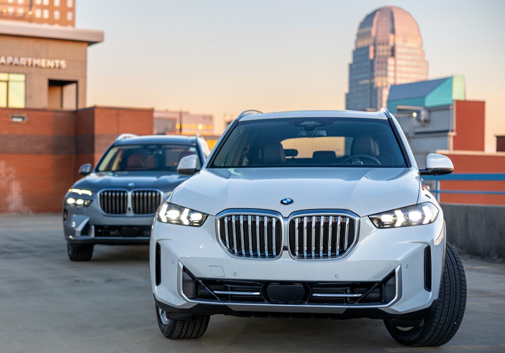 bmw-certified-pre-owned.png Two BMW cars parked on the roof of a parking deck with the downtown Winston-Salem city skyline in the background