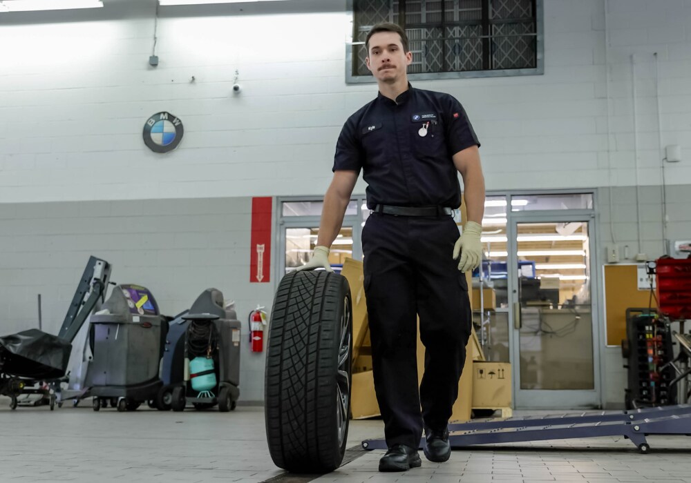 bmw-tires-winston-salem.png A service technician rolling a BMW tire through the Flow BMW service center