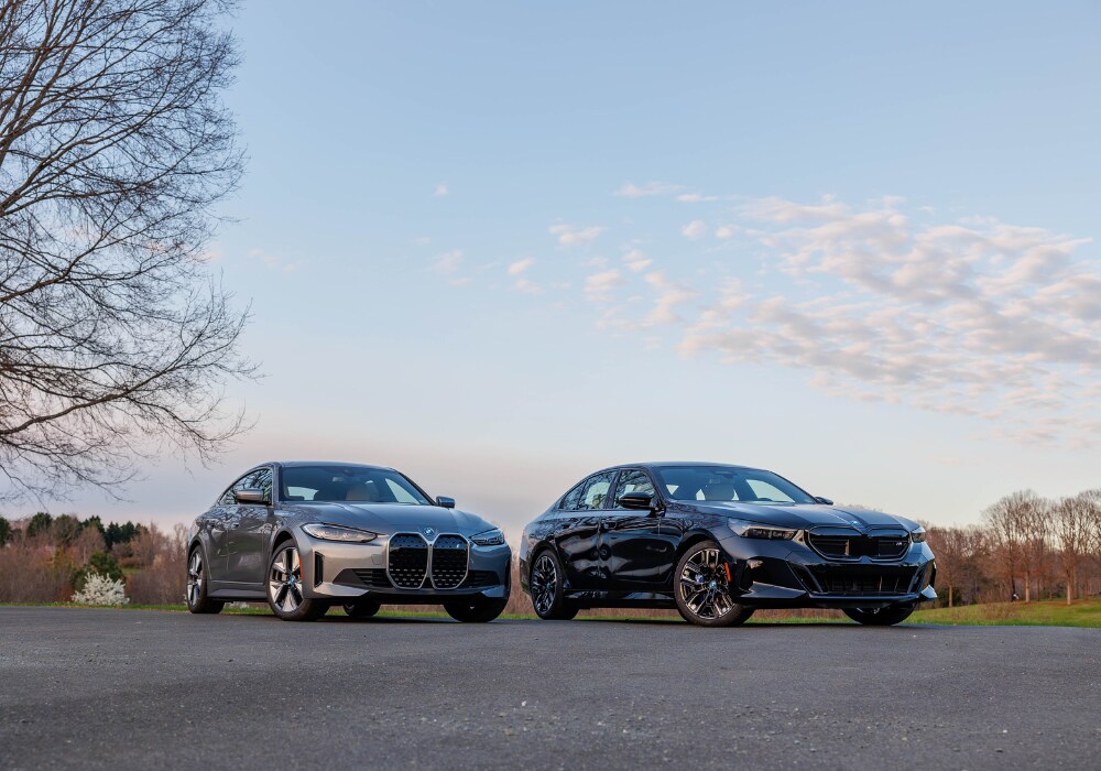 used-bmw-for-sale-winston-salem.png TWo BMW sedans parked in an empty lot in Winston-Salem. There are trees and a blue sky in the background