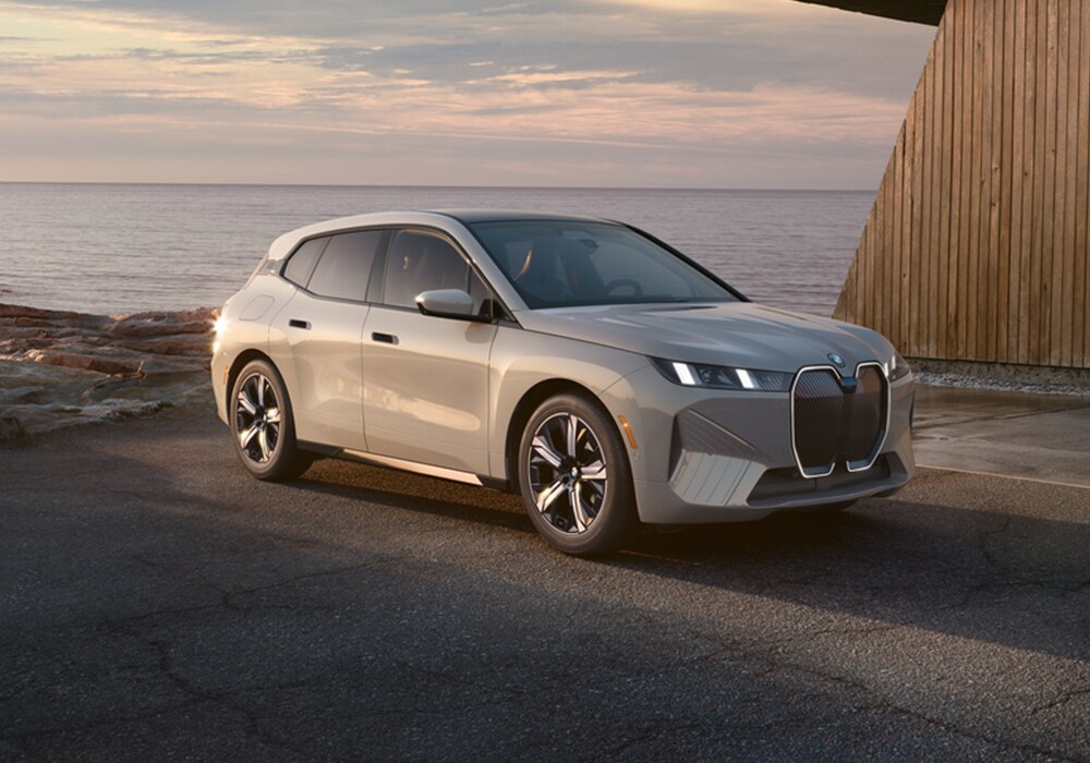 bmw-ix-electric.png 2025 BMW iX parked on a pave surface with a large body of water in the background