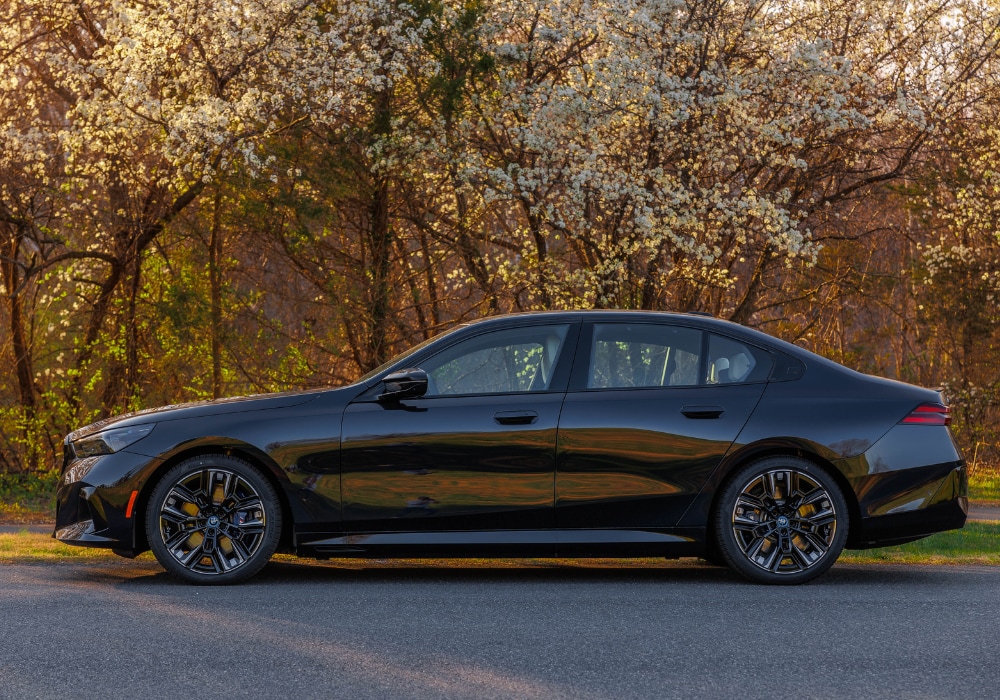 bmw-i5-electric.png Photo shows driver's side of a 2024 BMW i5 for sale in Winston-Salem. There are flowering trees behind the car