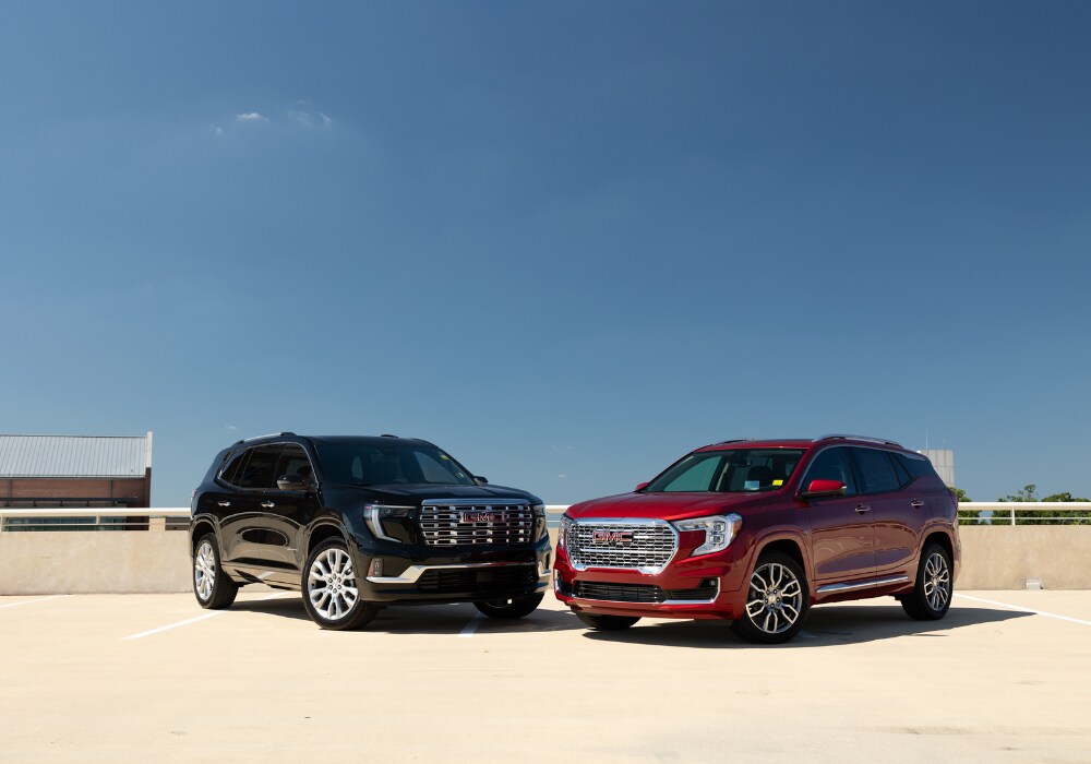 certified-pre-owned-gmc-suvs.png Two GMC SUVs parked on the top of a parking deck with a blue sky in the background