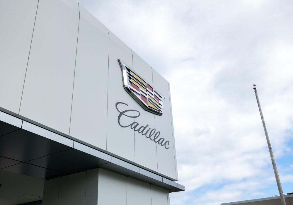 cadillac-wilmington-used-cars.png Close up photo of the Cadillac logo on the front of the Flow Cadillac of Wilmington dealership. There is a cloudy sky in the background