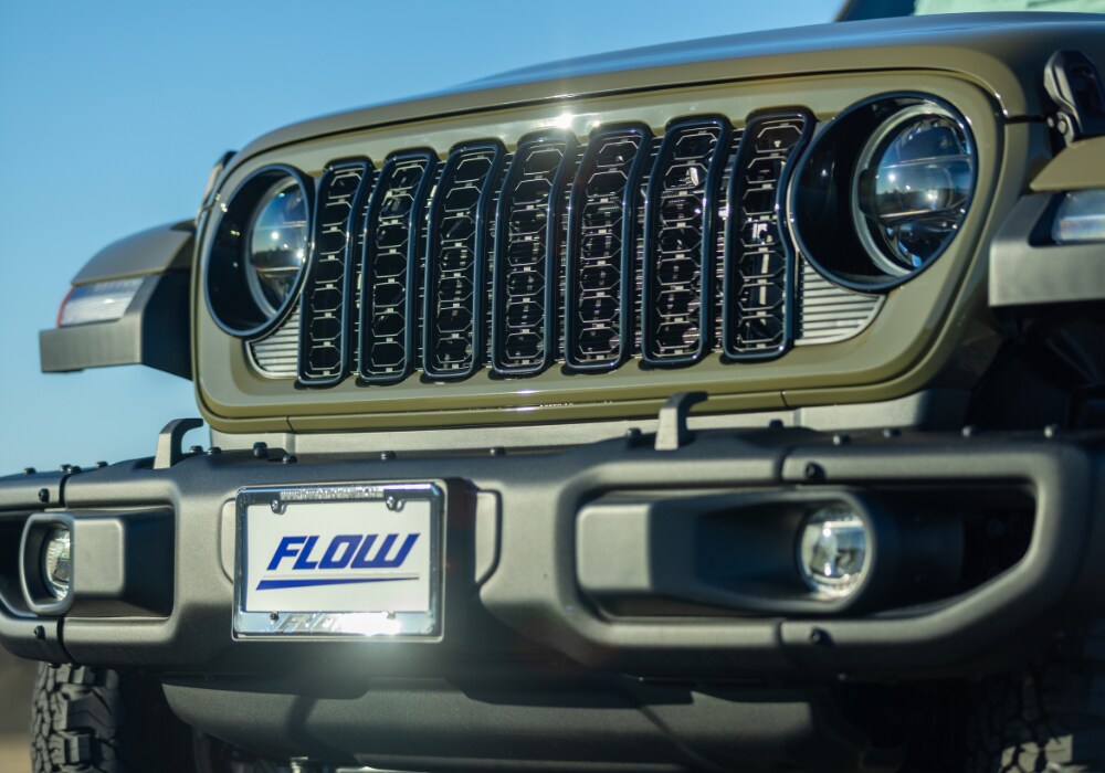 new-jeep-wrangler-for-sale-virginia.png Close up photo of the front grille of a new Jeep Wrangler. The car is green and the Flow logo is displayed on the front license plate