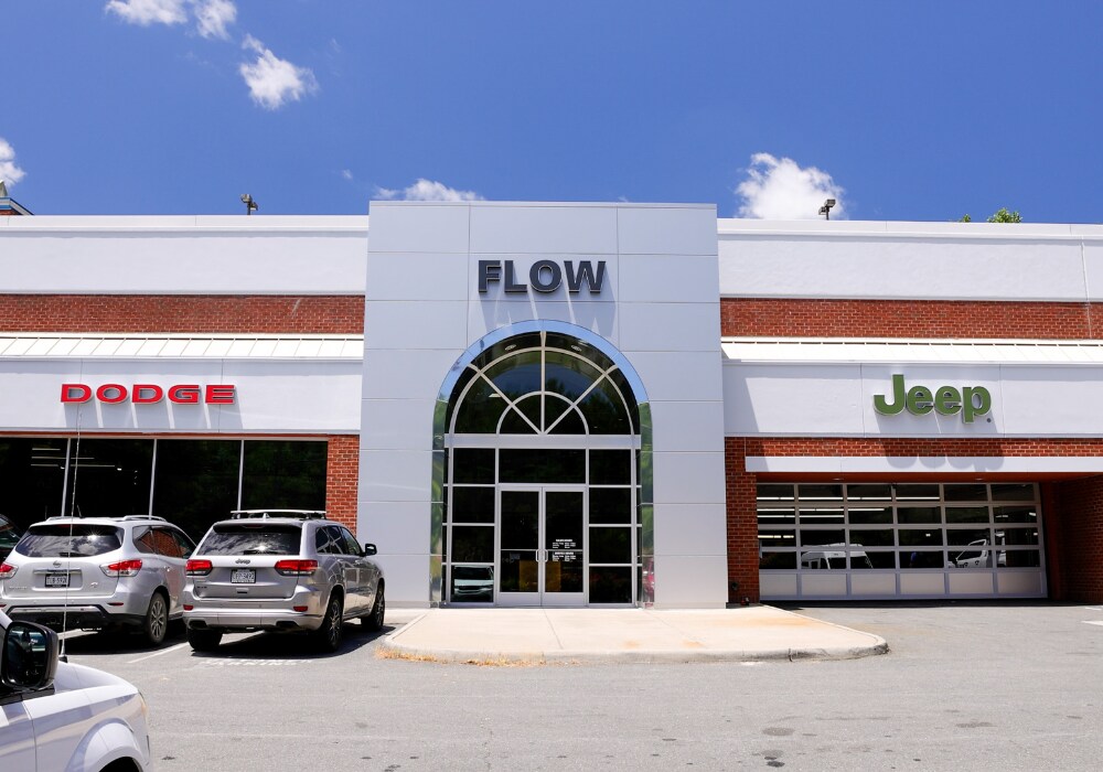 jeep-dealership-charlottesville-va.png Storefront of the Flow Chrysler Dodge Jeep Ram of Charlottesville dealership. There are two cars parked in front of the store