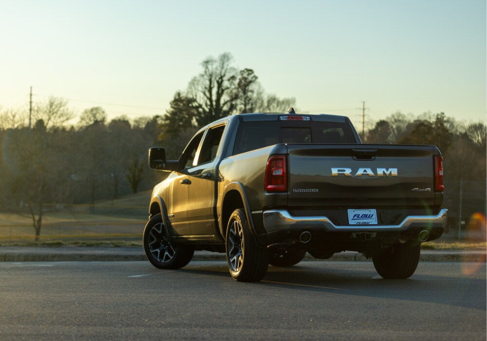 ram-1500-for-sale-culpeper.png Back view of a 2025 Ram 1500 parked in a lot. The truck is black and the sun is setting in the background