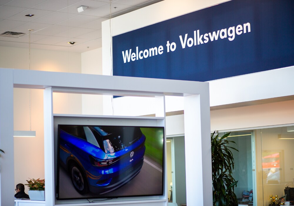volkswagen-dealership-burlington-nc.png Photo shows the interior of the Flow Volkswagen of Burlington dealership. There is a sign that reads Welcome to Volkswagen