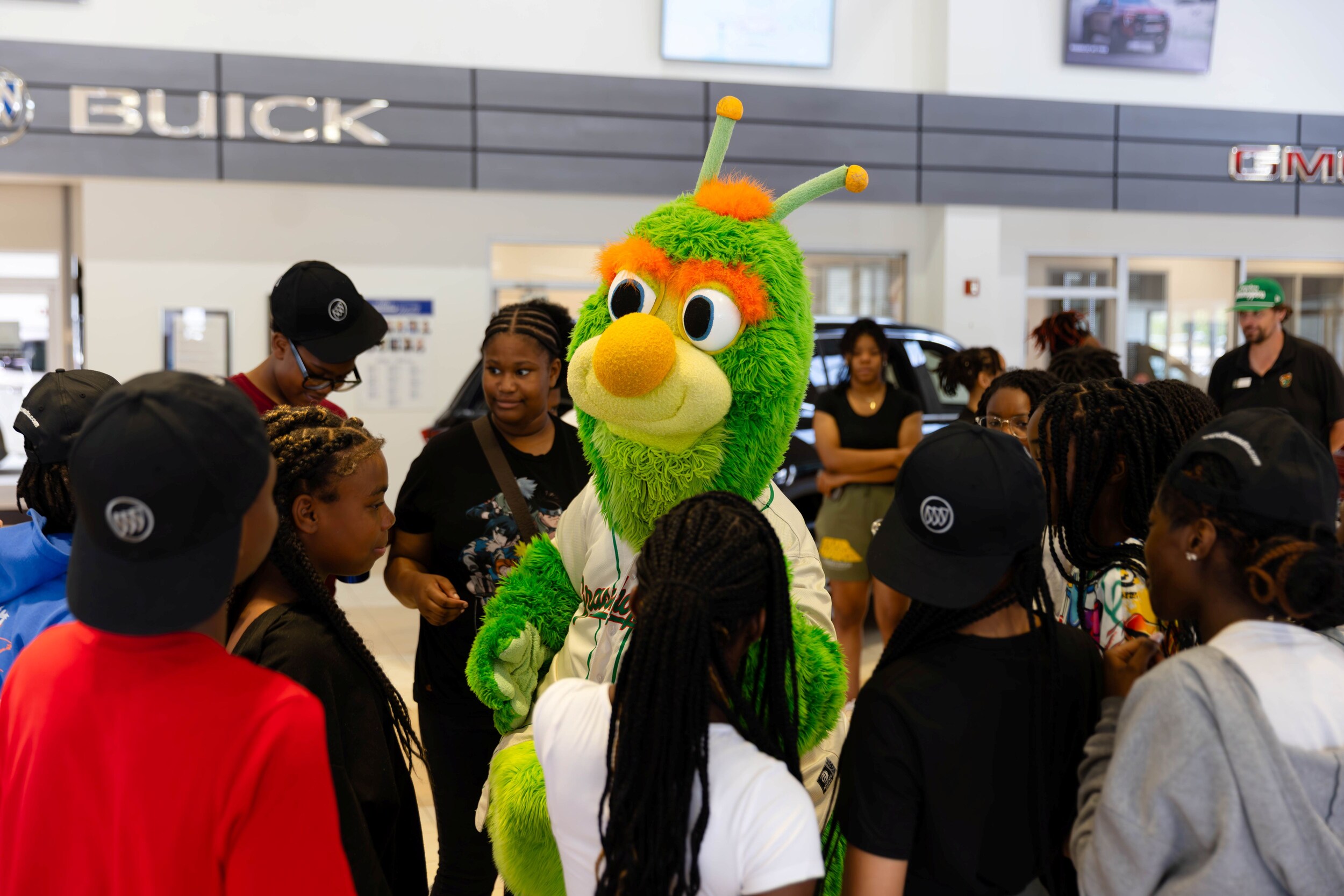 gmc-gso-day-at-dealership-38.jpg Guilford of the Greensboro Grasshopper greets members of the Red Shield Youth Center