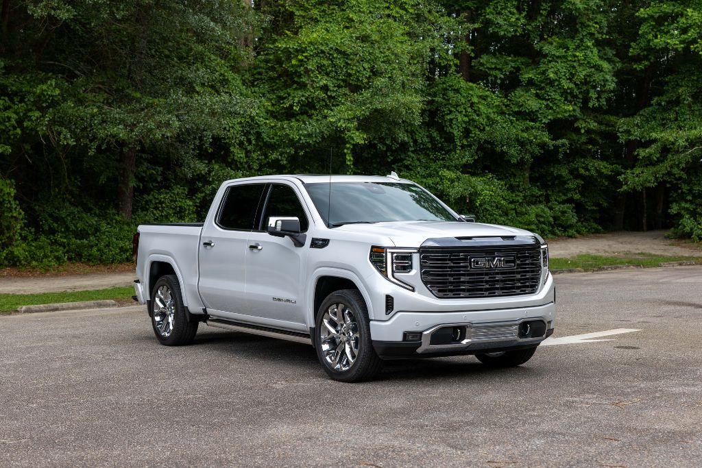 2024-gmc-sierra-1500-comparison White GMC Sierra 1500 for sale in Greensboro. The Sierra pickup truck is parked on a lot in front of trees