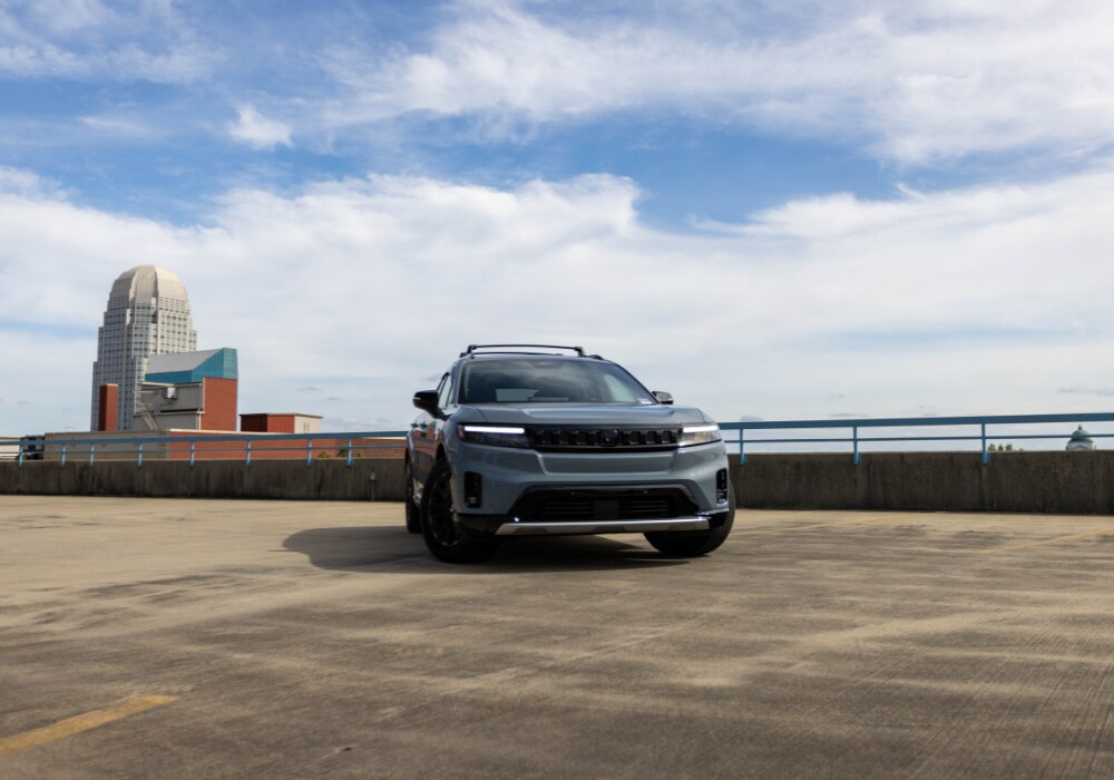 honda-prologue-for-sale.jpg Blue 2024 Honda Prologue parked on top of a parking garage with a blue sky and city line in the background