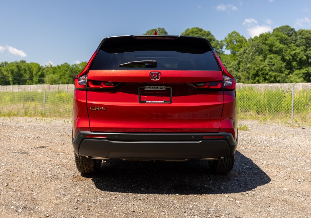 new-honda-cr-v-winston-salem.png Rear of a 2025 Honda CR-V for sale in Winston-Salem. The car is red and parked on a gravel road