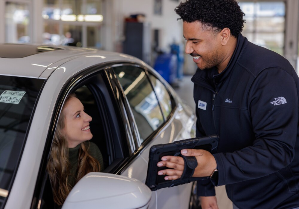 honda-service-coupons-near-winston-salem.png A Flow emplotyee smiling and helping a customer sitting in her car