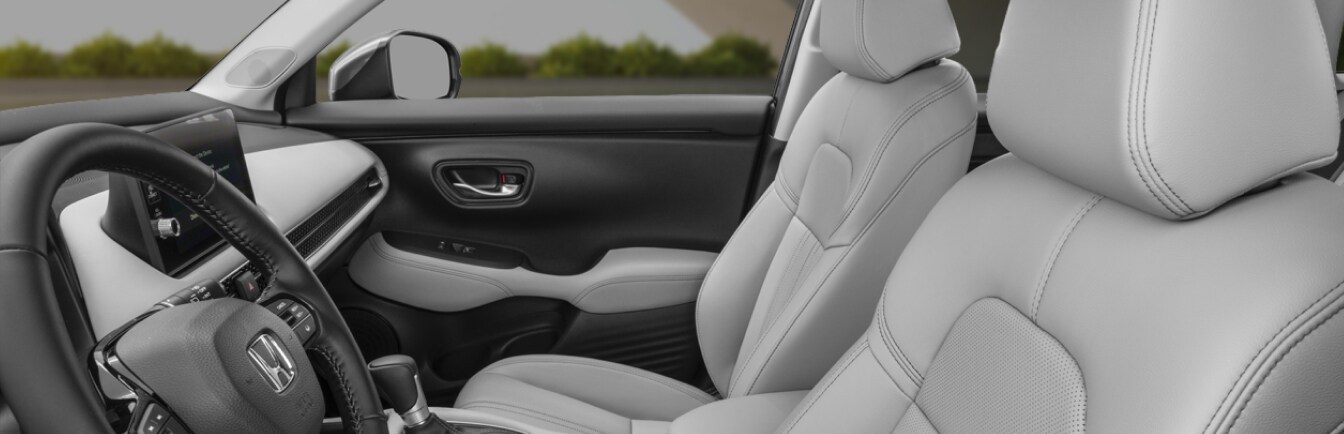 Perspective shot of 2027 Honda HR-V interior in gray perforated leather seen from outside the front driver side window.