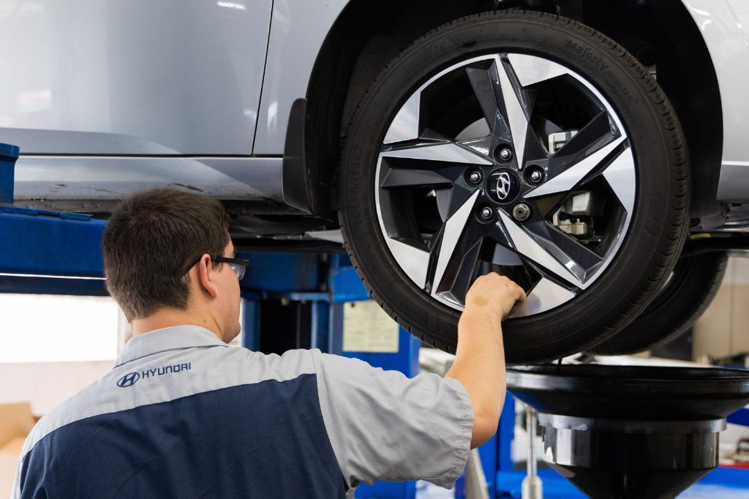 hyundai-service-center-virginia.jpg Certified Hyundai technician stands in front Hyundai car on a lift in service center