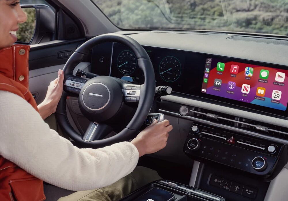 hyundai-tucson-interior-apple-carplay.png Woman driving a 2024 Hyundai Tucson with Apple CarPlay on the infotainment display screen