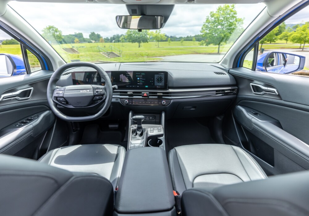 2025-kia-sportage-interior.png Kia Sportage interior, showing the entire front dash including the front wheel and infotainment system