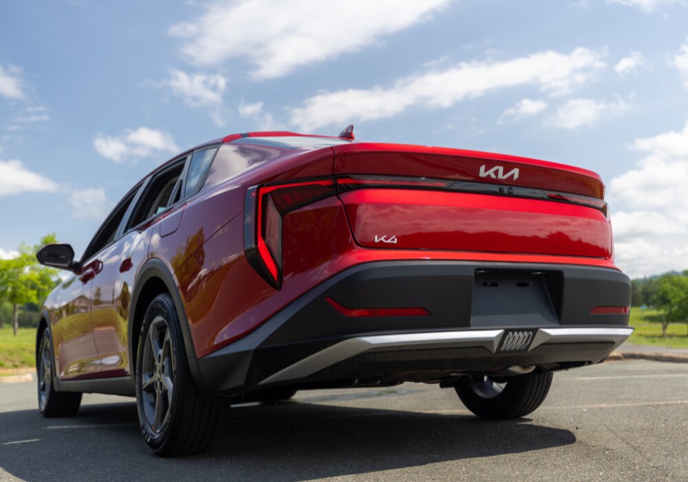 kia-k4-gt-line.png Rear exterior view of a 2025 Kia K4 parked in a paved lot. The car is bright red and the Kia K4 logo is visible on the back of the car