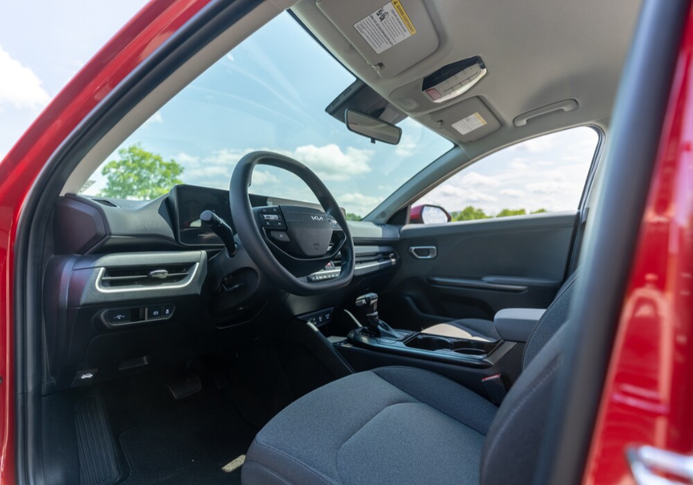 2025-kia-k4-interior.png Kia K4 interior. Photo taken from the perspective of the driver's side door. The Kia logo is visible on the steering wheel