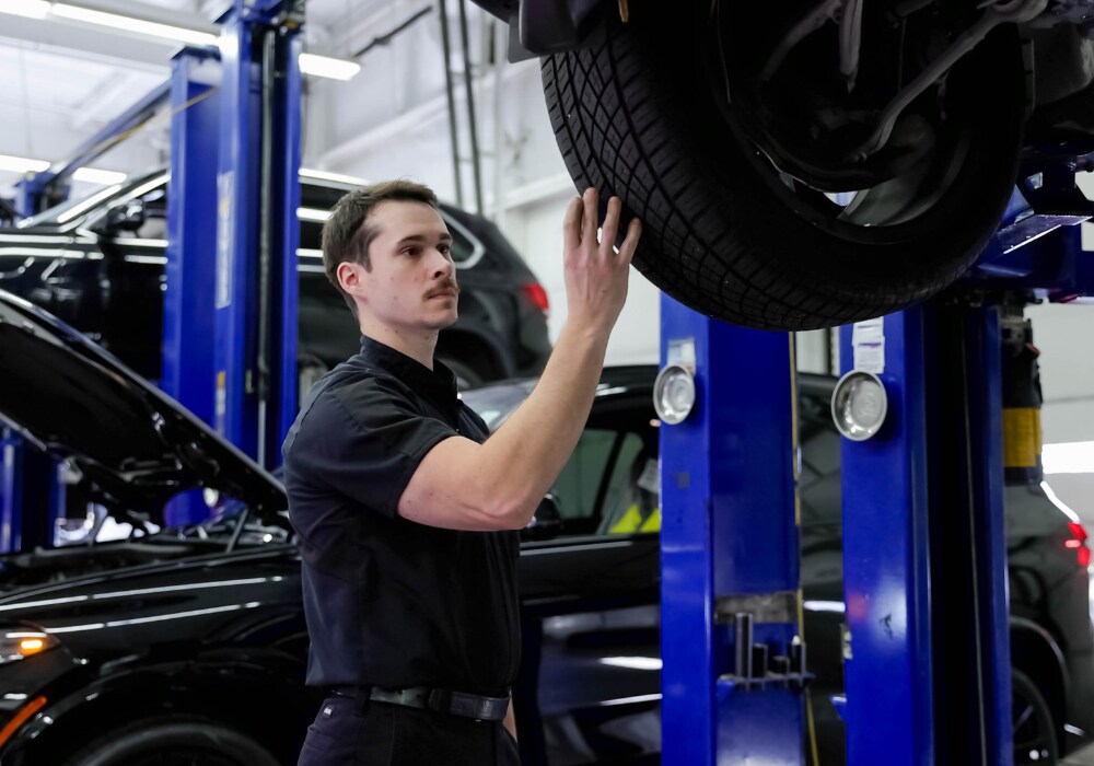 service-center-mazda-virginia.png S service technician checks the tire of a car at the service center of Flow Mazda of Charlottesville