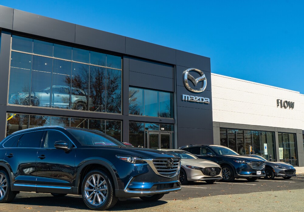 mazda-dealership-serving-richmond-va.png Lineup of Mazda cars for sale parked outside the Flow Mazda of Charlottesville dealership