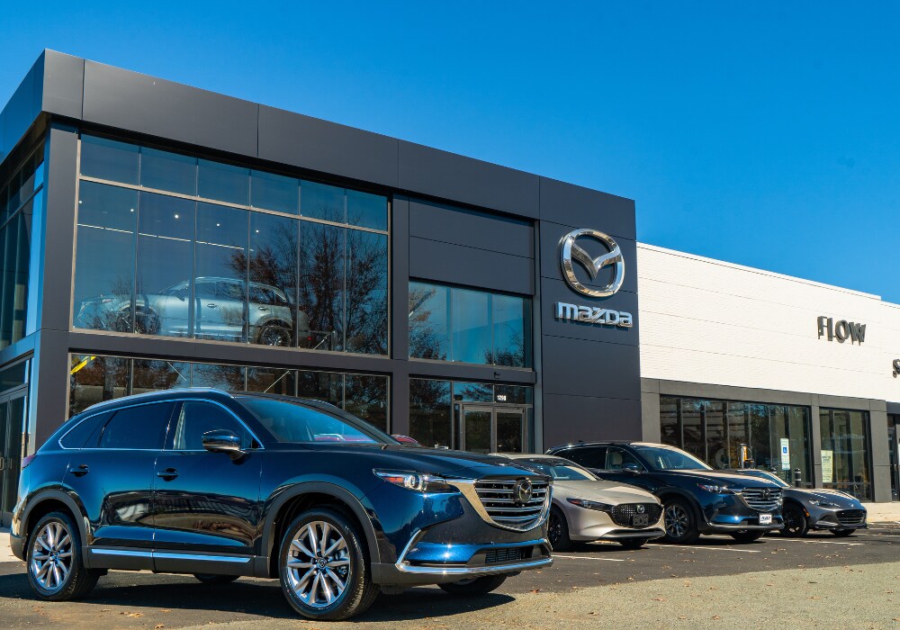 mazda-demo-vehicles-charlottesville-va.png Lineup of Mazda cars for sale parked outside of the Flow Mazda of Charlottesville dealership