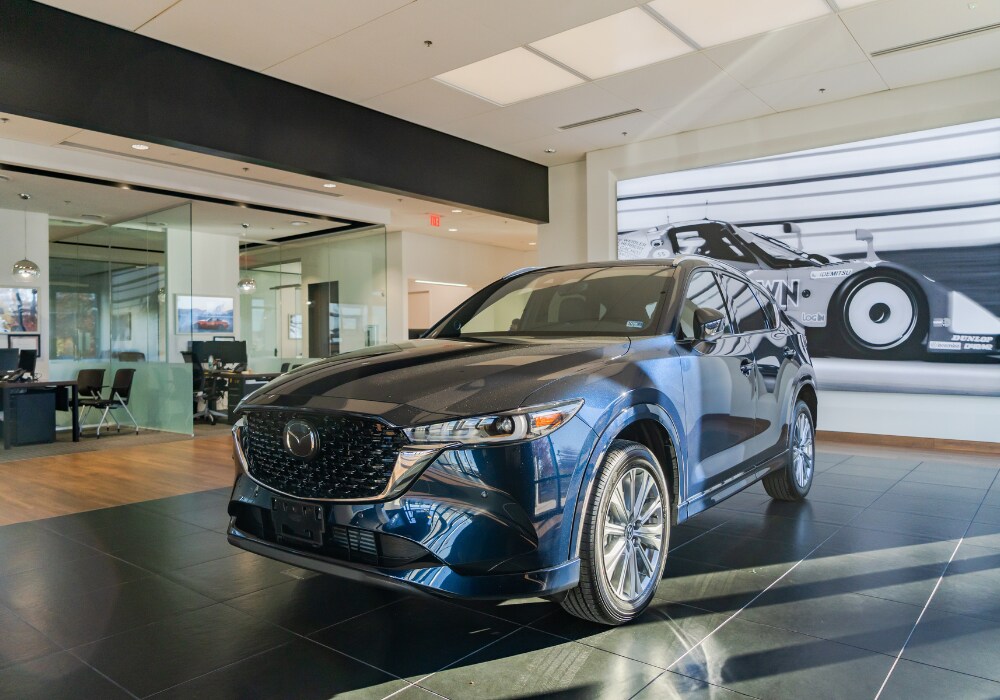 new-mazda-cars-for-sale-charlottesville.png New Mazda SUV parked inside the showroom of Flow Mazda of Charlottesville
