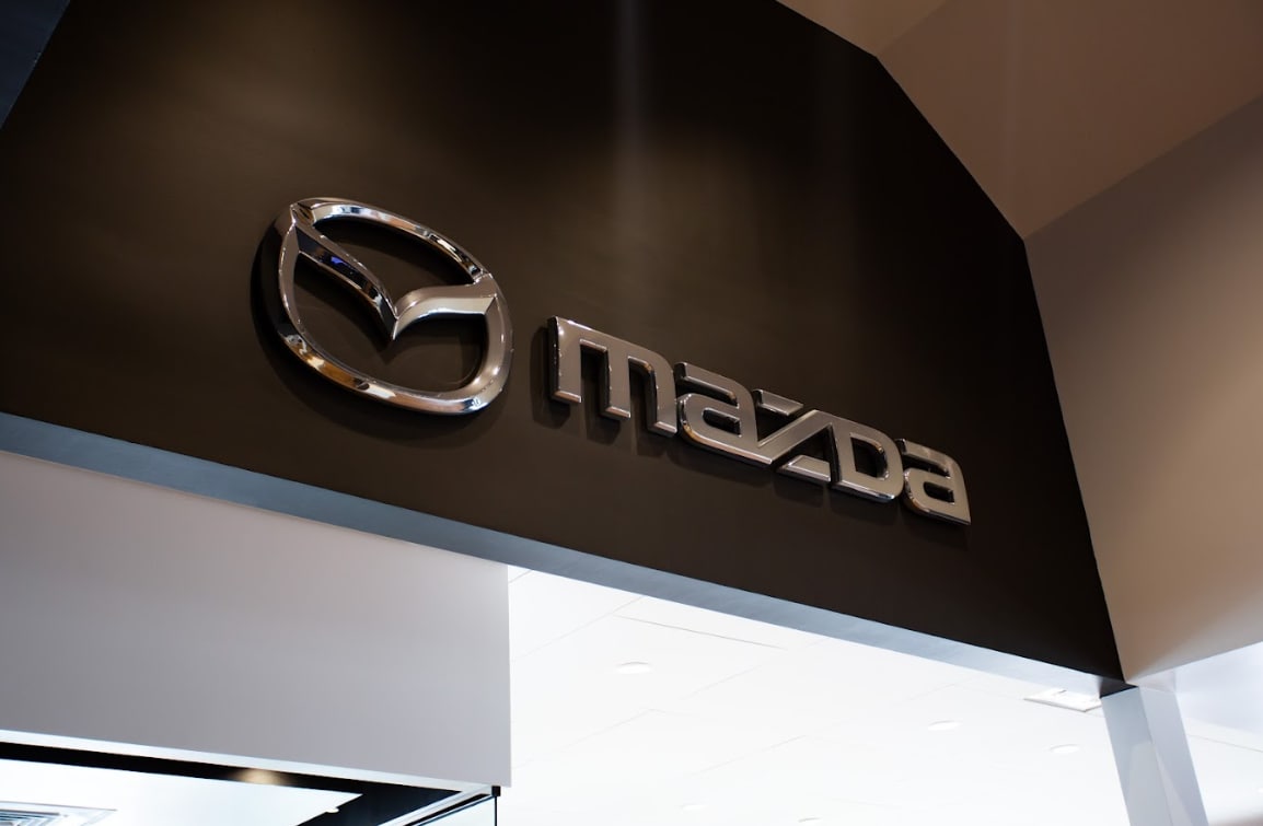 logo-mazda-fayetteville.png Mazda logo on the interior wall of the Flow Mazda of Fayetteville dealership in Carolina