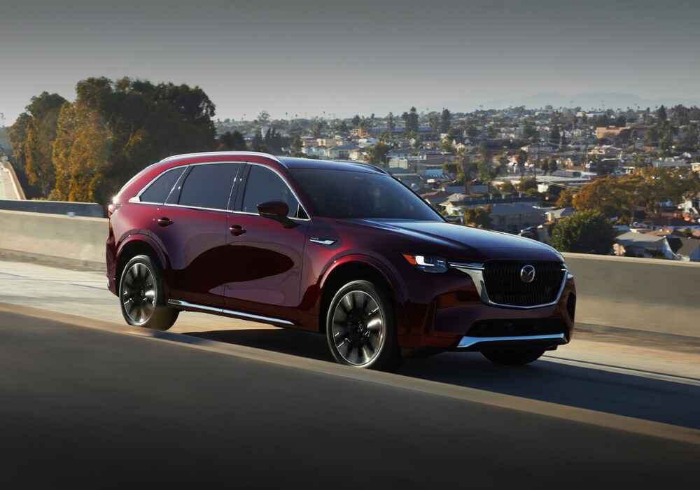 mazda-cx-90-for-sale.png Red 2025 Mazda Cx-90 SUV driving on a highway