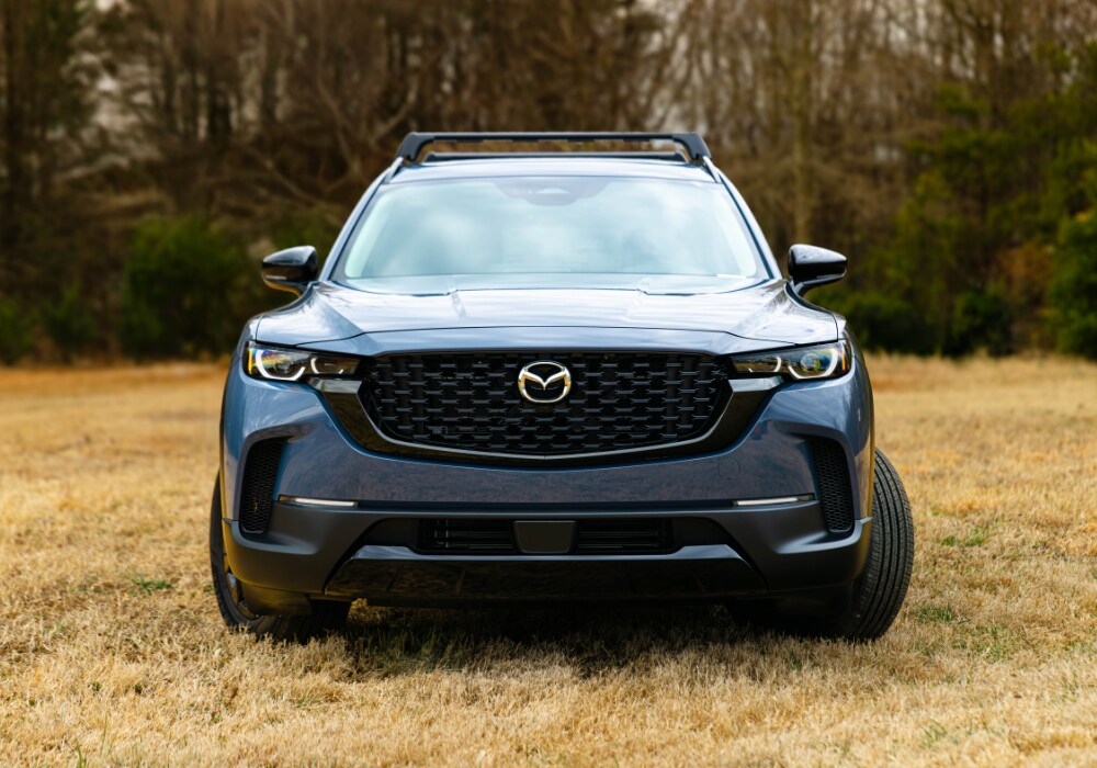 new-mazda-cars-for-sale-greensboro-nc.png Front view of Mazda SUV parked in a field with trees in the background